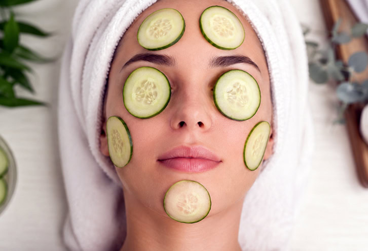 Une femme avec des rondelles de comcombre sur son visage
